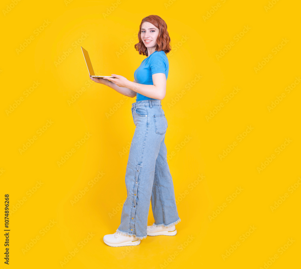 Using laptop, full length body size side view young attractive cheery girl using laptop walking isolated on yellow studio background. Student, IT employee, entrepreneur concept idea image. Using laptop, full length body size side view young attractive cheery girl using laptop walking isolated on yellow studio background. Student, IT employee, entrepreneur concept idea image.