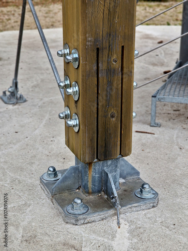 foundation feet screwed to the concrete slab. it holds the wooden tower with nuts and bolts even in the wind. lashing against swings photo