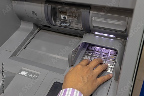 Close up view of a female hand pressing number keys on Automated Teller Machine or ATM machine photo