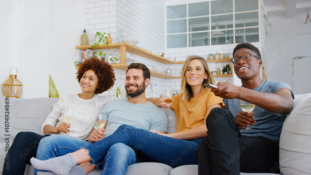 Group Of Friends Sitting On Sofa And Watching Movie At Home Whilst Drinking Wine Group Of Friends Sitting On Sofa And Watching Movie At Home Whilst Drinking Wine