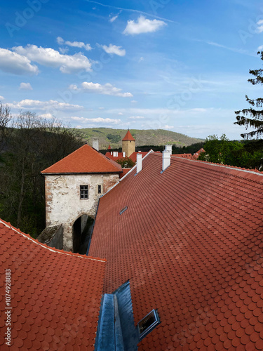 Scenic view of red rooftops and historic towers under a blue sky in Veveri castle, Czech Republic.