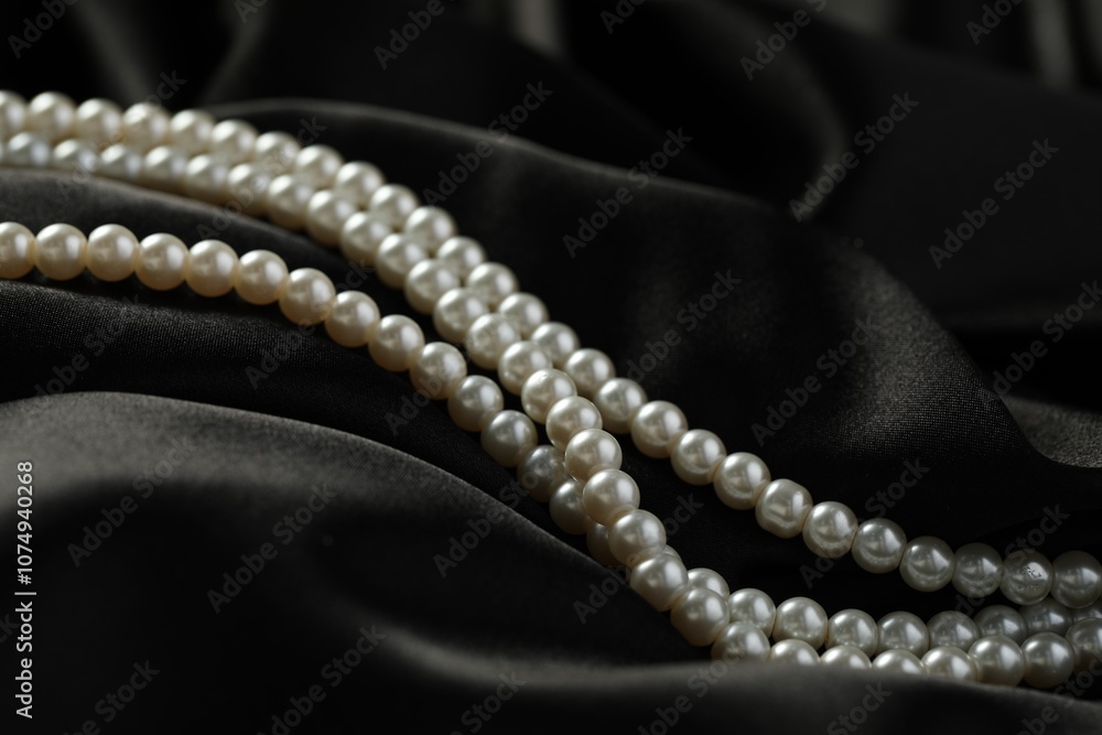 Beautiful pearl necklace on black silk, closeup Beautiful pearl necklace on black silk, closeup