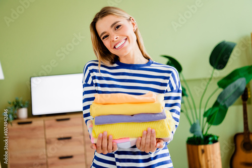 Photo of nice blonde young girl hold pile laundry conditioner wear striped clothes enjoy modern cozy interior flat indoors photo