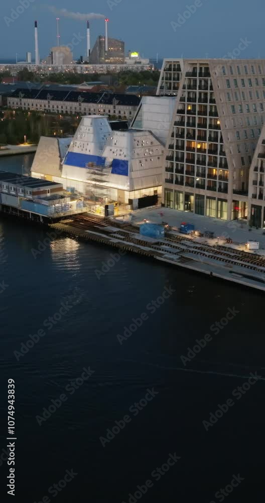 Aerial drone view of the Paper Island urban oasis surrounded by water in Copenhagen, Denmark at night. Vertical