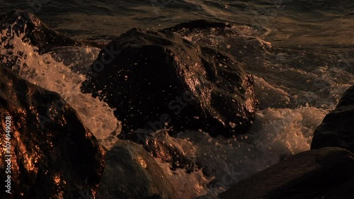 Sea waves hitting the rocky coast at sunset