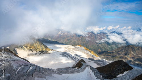 The Taschachferner Glacier reveals its vast icy expanse beneath cloudy skies, as seen from the summit of Wildspitze in Austria, showcasing the breathtaking alpine landscape and rugged mountain terrain photo