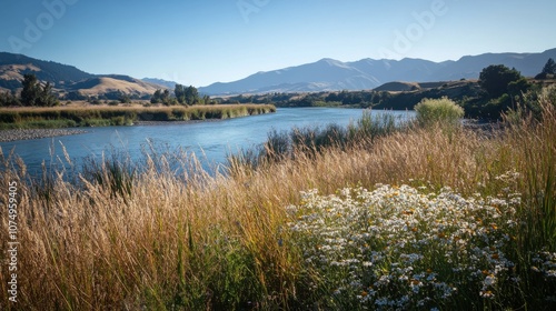 A tranquil summer day by the winding river bank surrounded by wildflowers and distant mountains in a calm landscape