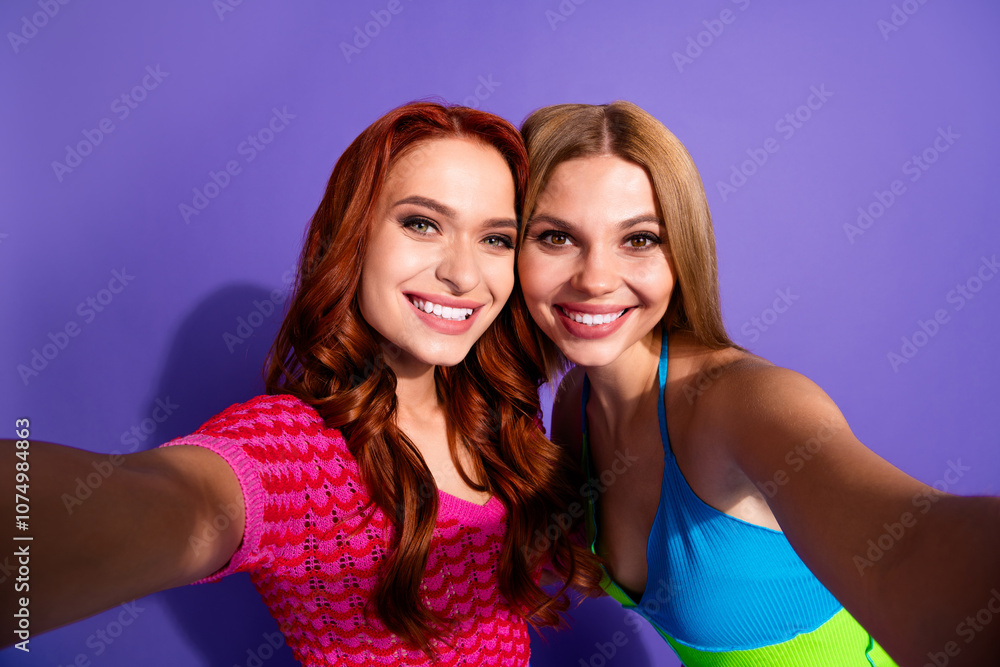 Portrait of two nice stunning girls toothy smile take selfie isolated on purple color background Portrait of two nice stunning girls toothy smile take selfie isolated on purple color background