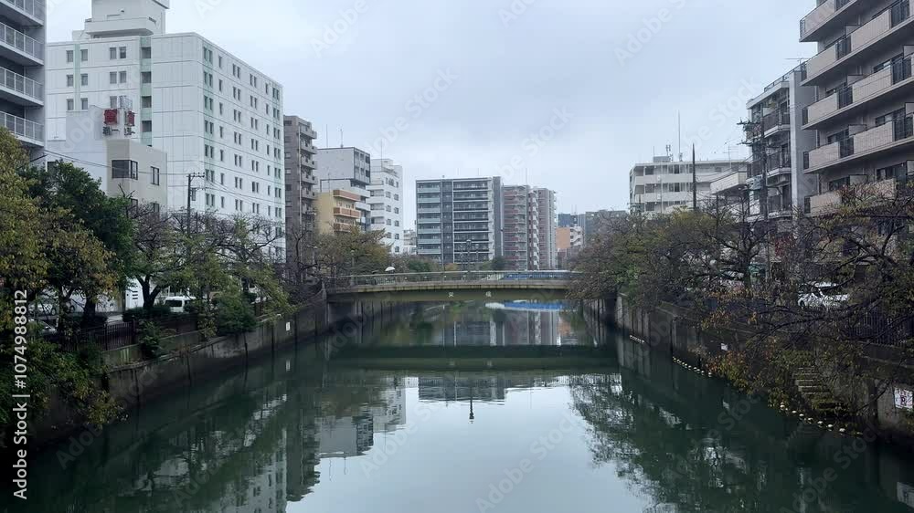 A calm canal flows between apartment buildings on an overcast day in Yokohama, Japan A calm canal flows between apartment buildings on an overcast day in Yokohama, Japan