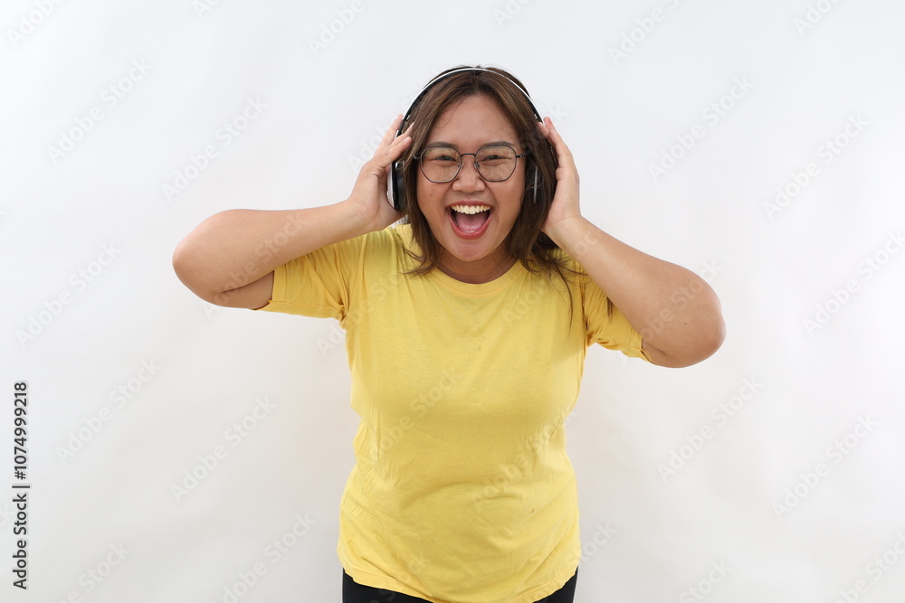 Excited young woman in casual t-shirt posing isolated on white wall background studio portrait. People sincere emotions lifestyle concept. Mock up copy space. Listen music with headphones Excited young woman in casual t-shirt posing isolated on white wall background studio portrait. People sincere emotions lifestyle concept. Mock up copy space. Listen music with headphones
