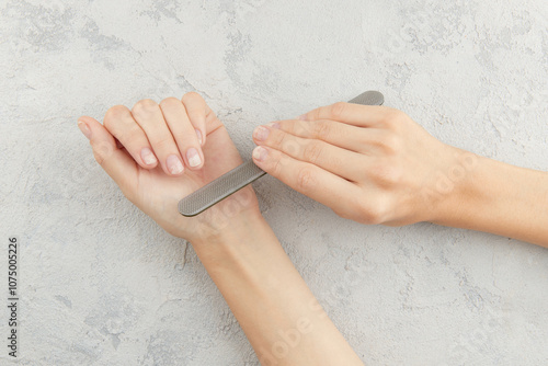 Woman filing damaged nails. Fingernails with onycholysis after removing gel polish photo