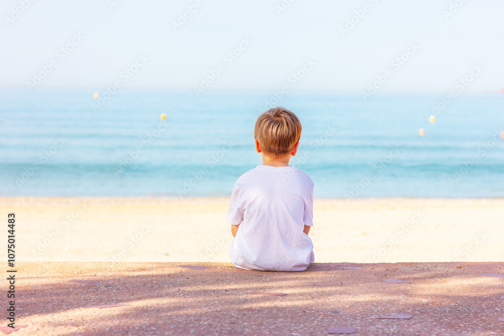 boy sits on the sea coast, back view boy sits on the sea coast, back view
