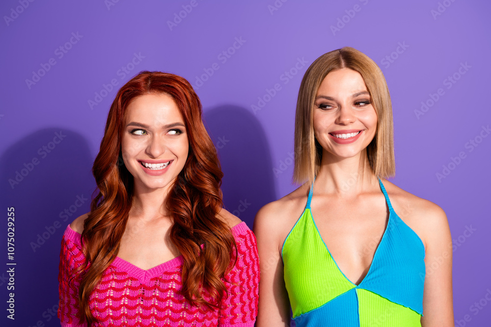Portrait of two nice stunning girls toothy smile look each other think isolated on purple color background Portrait of two nice stunning girls toothy smile look each other think isolated on purple color background