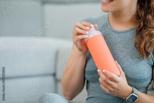 Young athlete woman training with a roller or wheel in her living room takes a break to hydrate herself drinking water takes a break to work with a laptop, teleworking, healthy living, routines
