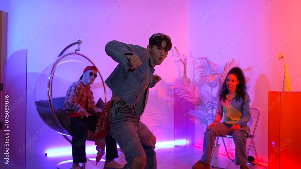 Skilled asian dancer moving to modern music while multicultural friend sitting at chair. Professional performer dancing show energetic foot step while hipster team cheering and supporting. Regalement. Skilled asian dancer moving to modern music while multicultural friend sitting at chair. Professional performer dancing show energetic foot step while hipster team cheering and supporting. Regalement.