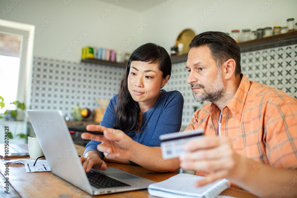 Couple making online payment with credit card and laptop at home Couple making online payment with credit card and laptop at home