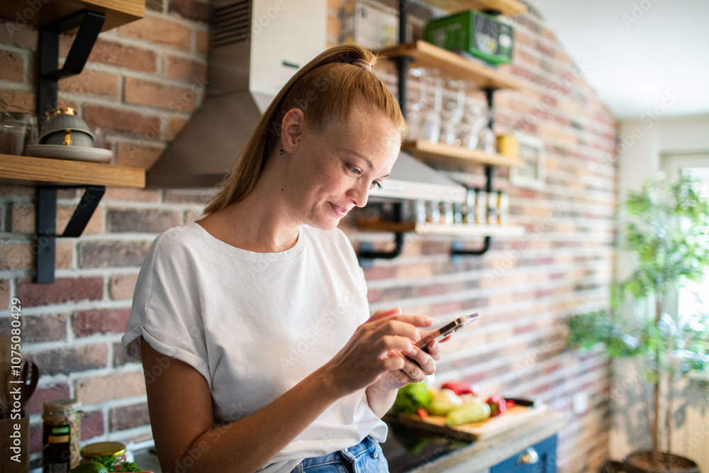 Young woman holding smartphone in modern kitchen Young woman holding smartphone in modern kitchen