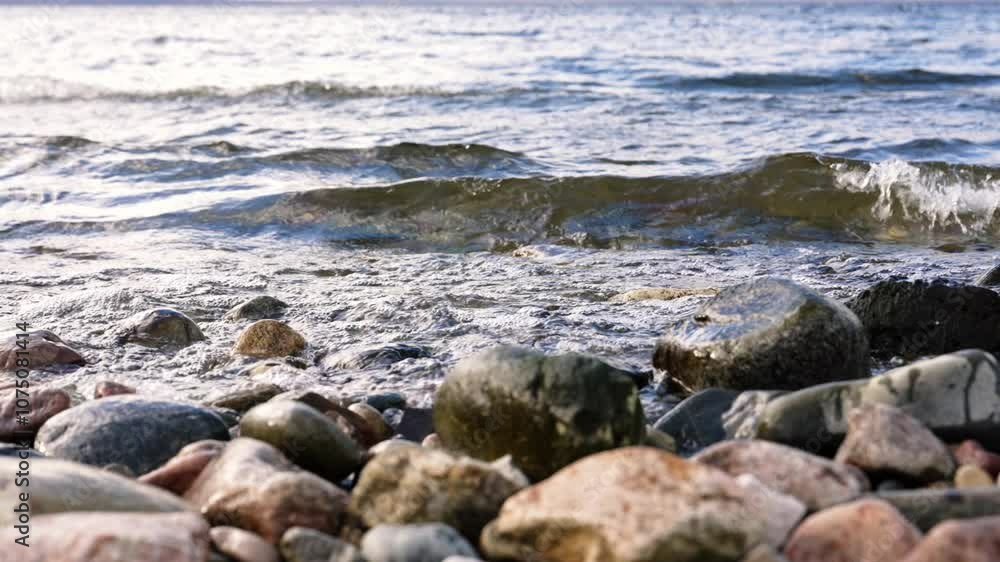 Gentle waves crash against a rocky beach, creating a serene atmosphere. Sunlight sparkles on clear blue water, enhancing the tranquil beauty of the coastline under a bright sky Gentle waves crash against a rocky beach, creating a serene atmosphere. Sunlight sparkles on clear blue water, enhancing the tranquil beauty of the coastline under a bright sky