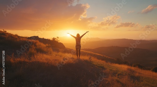 A person joyfully embracing the sunset while standing atop a hill with expansive views of the landscape at dusk