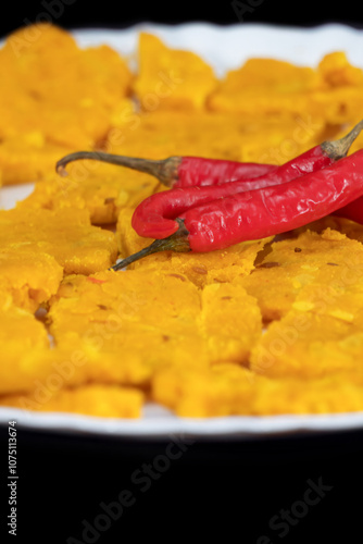 Portrait and Selective Focus Of Gujarati Kathiyawadi Spicy Dhokali Sabji On White Plate, Red Chillies On The Top, Isolated On Black Background photo