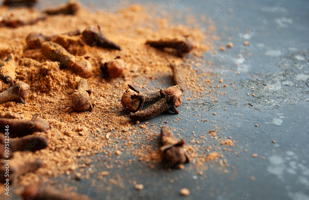Fresh whole and ground clove spice on a dark blue backdrop, evoking winter warmth. Fresh whole and ground clove spice on a dark blue backdrop, evoking winter warmth.