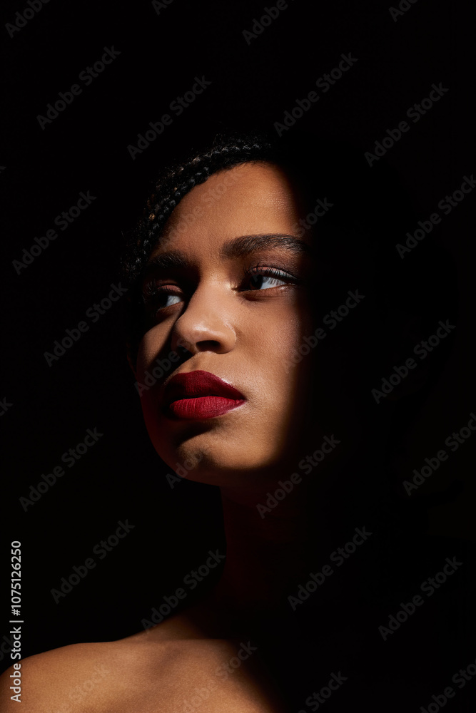 A young African American woman with braided hair and striking red lips showcases a confident pose in a studio. A young African American woman with braided hair and striking red lips showcases a confident pose in a studio.