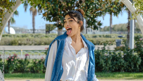 Принти на полотні A young brunette businesswoman in a tree-filled park on a spring day, sticking h