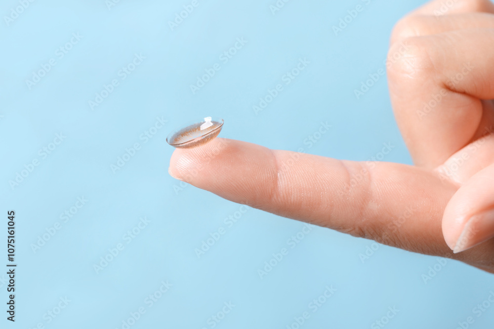 Εκτύπωση καμβά Woman holding color contact lens on light blue background, closeup