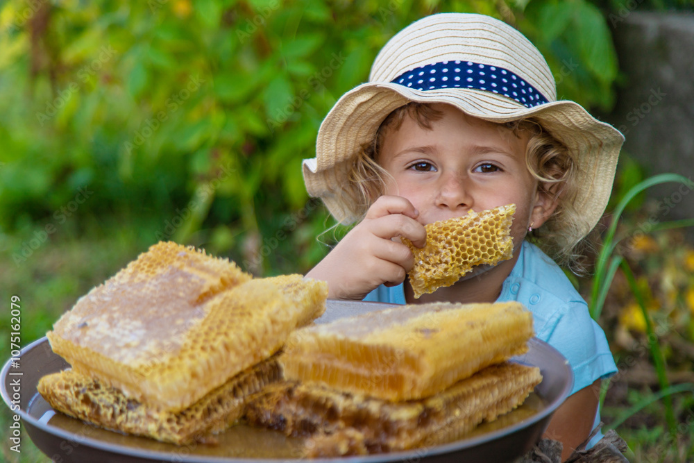 A child eats honey from a comb. Selective focus. A child eats honey from a comb. Selective focus.