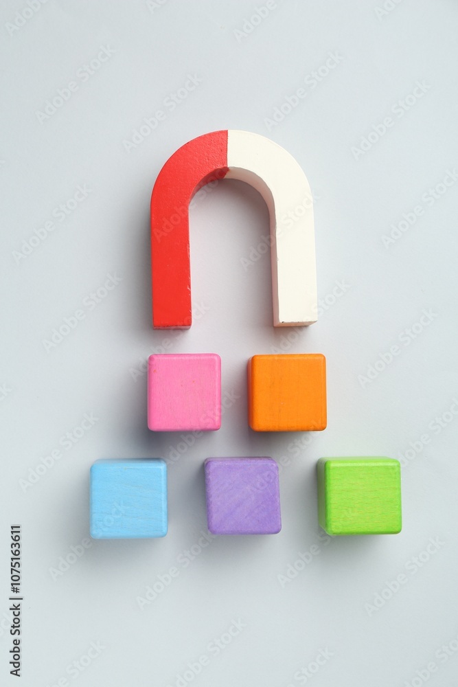 Magnet attracting colorful cubes on light grey background, flat lay Magnet attracting colorful cubes on light grey background, flat lay