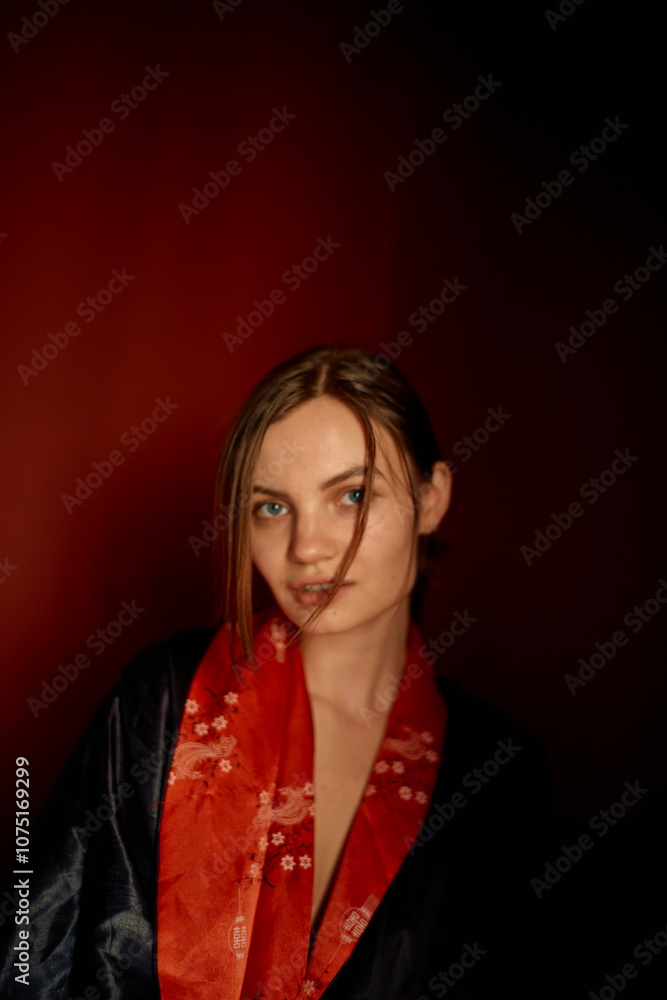 Woman in a red and black robe posing against a dark red background. Woman in a red and black robe posing against a dark red background.