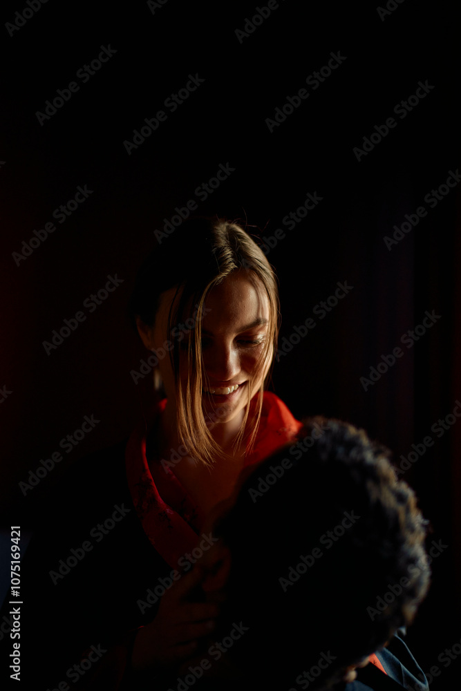 Woman in a red sweater embracing her partner in a dimly lit room. Woman in a red sweater embracing her partner in a dimly lit room.