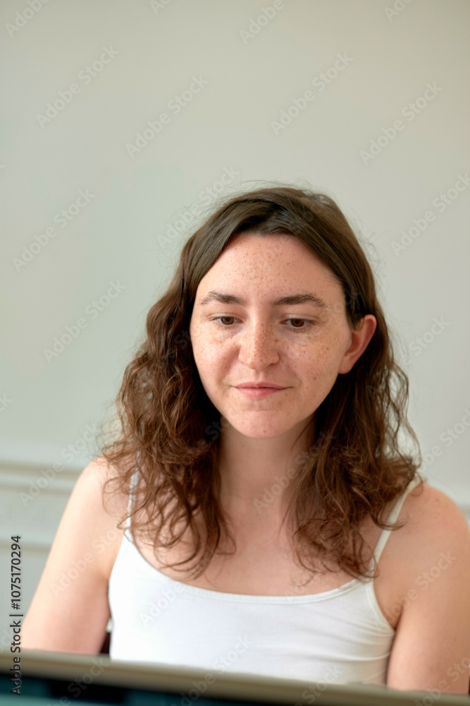 Woman sitting in front of a laptop, focused on her work with a contemplative expression. Woman sitting in front of a laptop, focused on her work with a contemplative expression.