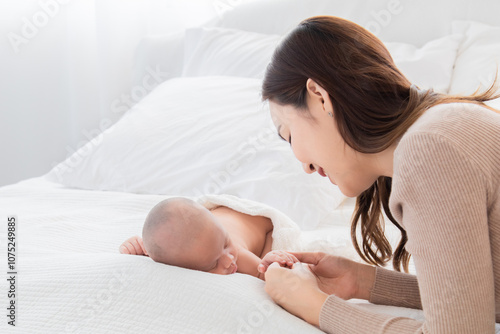 Adorable sleeping baby comfortable on bed in mother arm nursing, young Asian beautiful mom lying down hug infant 0-1 month with love, gently, tenderly, cuddle, bonding, caring motherhood nurturing photo