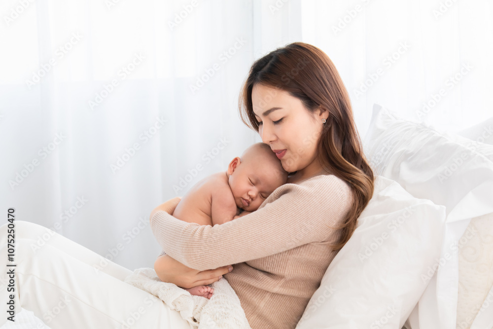 Asian loving mother caring for her newborn baby at home, sleeping baby in her arm with love and care, adorable cuddle sleep on chest mom and safe, healthcare infant and mother nurturing concept Asian loving mother caring for her newborn baby at home, sleeping baby in her arm with love and care, adorable cuddle sleep on chest mom and safe, healthcare infant and mother nurturing concept