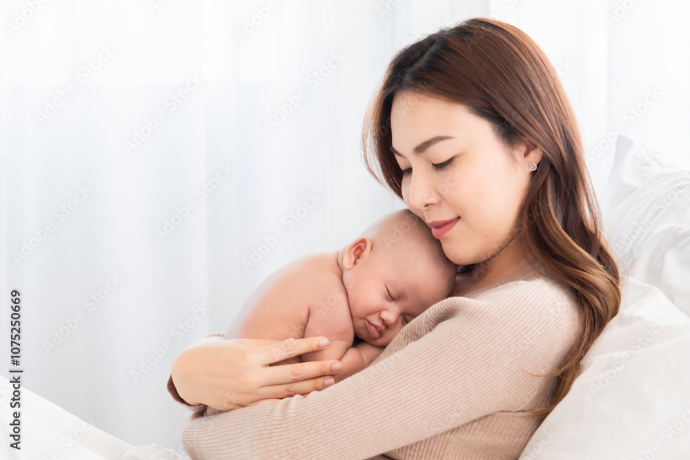 Asian loving mother caring for her newborn baby at home, sleeping baby in her arm with love and care, adorable cuddle sleep on chest mom and safe, healthcare infant and mother nurturing concept Asian loving mother caring for her newborn baby at home, sleeping baby in her arm with love and care, adorable cuddle sleep on chest mom and safe, healthcare infant and mother nurturing concept