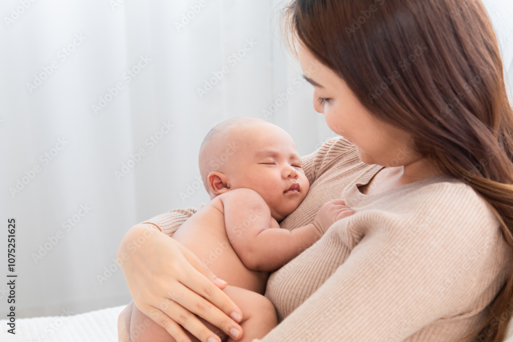 Young cheerful and beautiful Asian mom sleeping baby in arm, mother and newborn bonding relationship. Mother holding adorable healthcare nurturing. woman tenderly cuddles infant with love and care Young cheerful and beautiful Asian mom sleeping baby in arm, mother and newborn bonding relationship. Mother holding adorable healthcare nurturing. woman tenderly cuddles infant with love and care