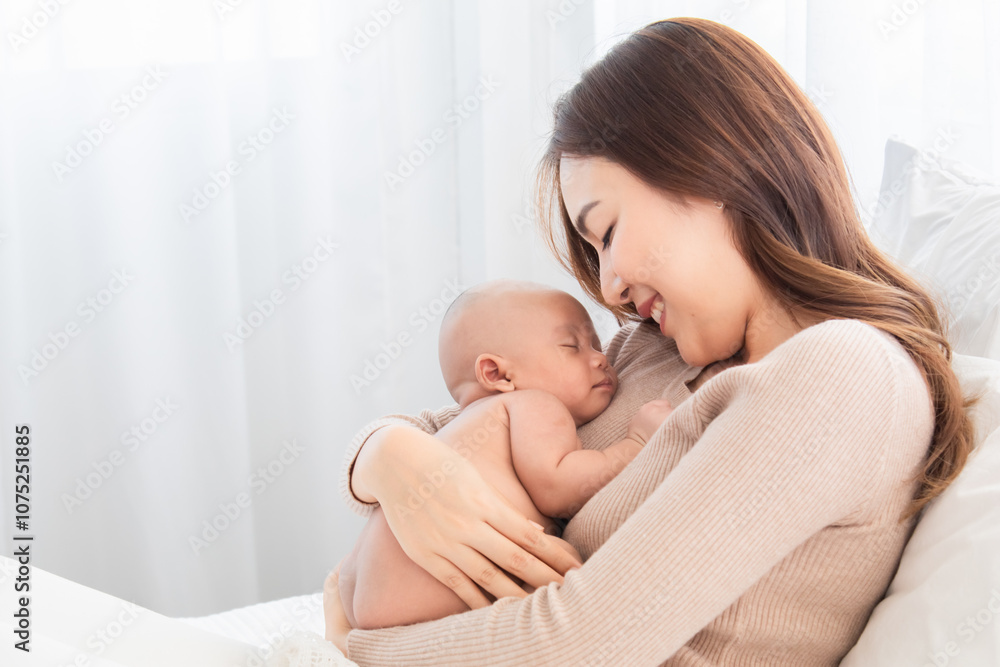Young cheerful and beautiful Asian mom sleeping baby in arm, mother and newborn bonding relationship. Mother holding adorable healthcare nurturing. woman tenderly cuddles infant with love and care Young cheerful and beautiful Asian mom sleeping baby in arm, mother and newborn bonding relationship. Mother holding adorable healthcare nurturing. woman tenderly cuddles infant with love and care