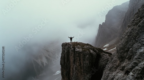 A solitary figure stands triumphantly on a misty mountain peak, arms outstretched, embracing vast wilderness and freedom.