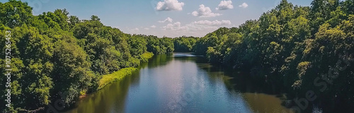 Panoramic view of the tranquil, floating river with lush, green trees on both sides, a blue sky