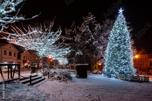 Christmas tree with lights in the town in the evening atmosphere with snow cover