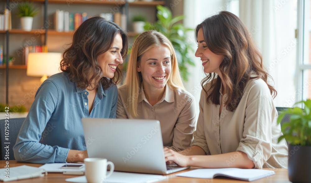 female employees discuss the idea while sitting at a table in front of a laptop female employees discuss the idea while sitting at a table in front of a laptop