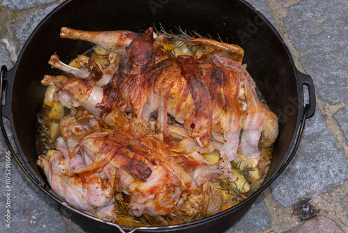 Perlhühner mit Schinkenmantel und Rosmarin Kartoffeln im Dutch Oven. photo