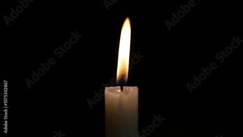 A single candle burns brightly in the dark, symbolizing sorrow and remembrance. This moment captures the essence of a heartfelt religious ceremony honoring loss and grief.