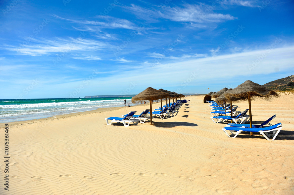 Fototapeta premium Sun loungers and parasols in Atlanterra beach of Zahara de los Atunes near Tarifa, Coast of Light Coast of Cadiz, Andalusia. One of the most famous beaches in Spain, southern Europe