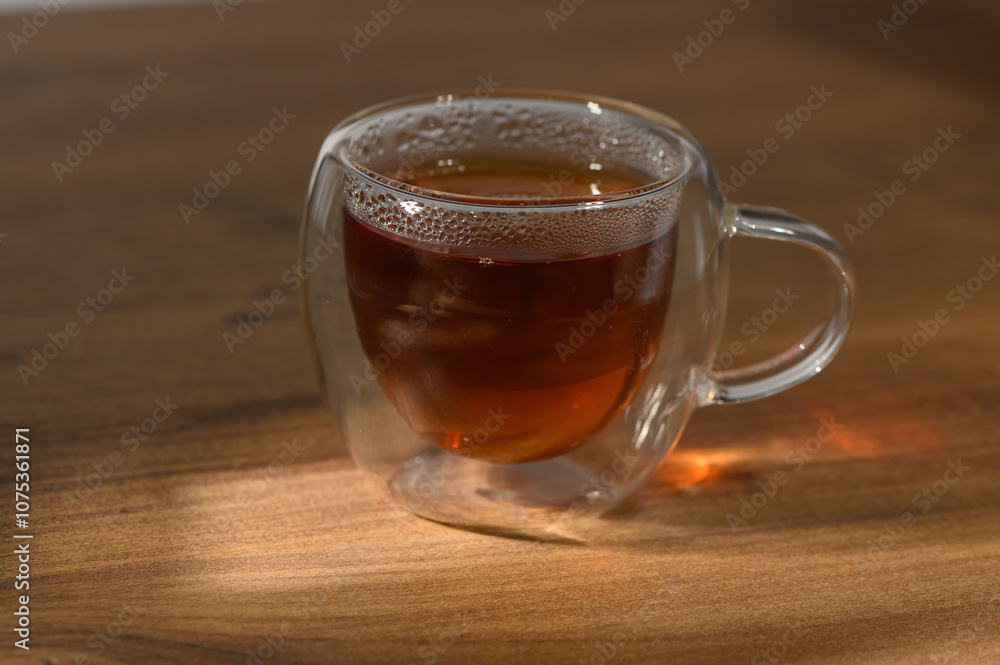 A warm cup of herbal tea resting on a wooden table illuminated by soft afternoon light A warm cup of herbal tea resting on a wooden table illuminated by soft afternoon light