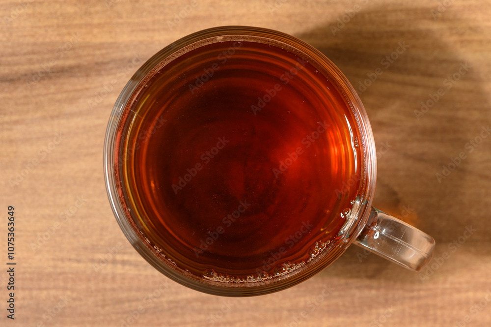A warm cup of brewed tea resting on a wooden table in a cozy setting A warm cup of brewed tea resting on a wooden table in a cozy setting