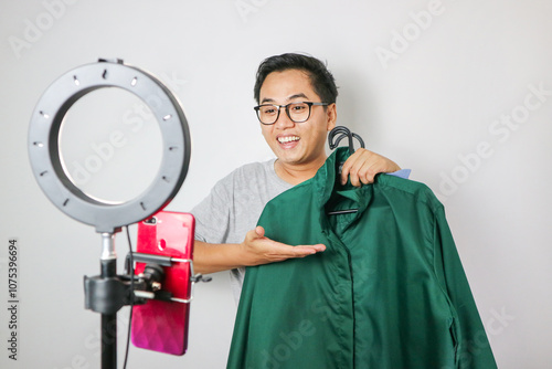 Adult asian seller man look intend holding looking at camera to present product via live online for shopping online with e-commerce sell. photo