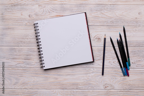 Top View of Open Sketchbook with Colored Pencils on Wooden Background