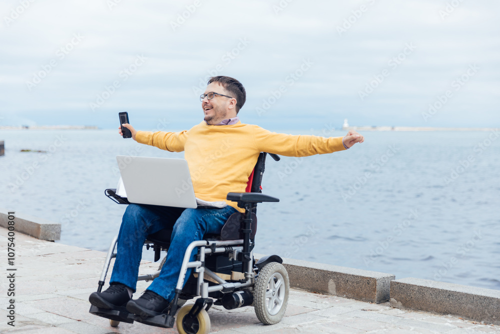 Fototapeta premium A man in a wheelchair on a walk in the city and his hands to the sides